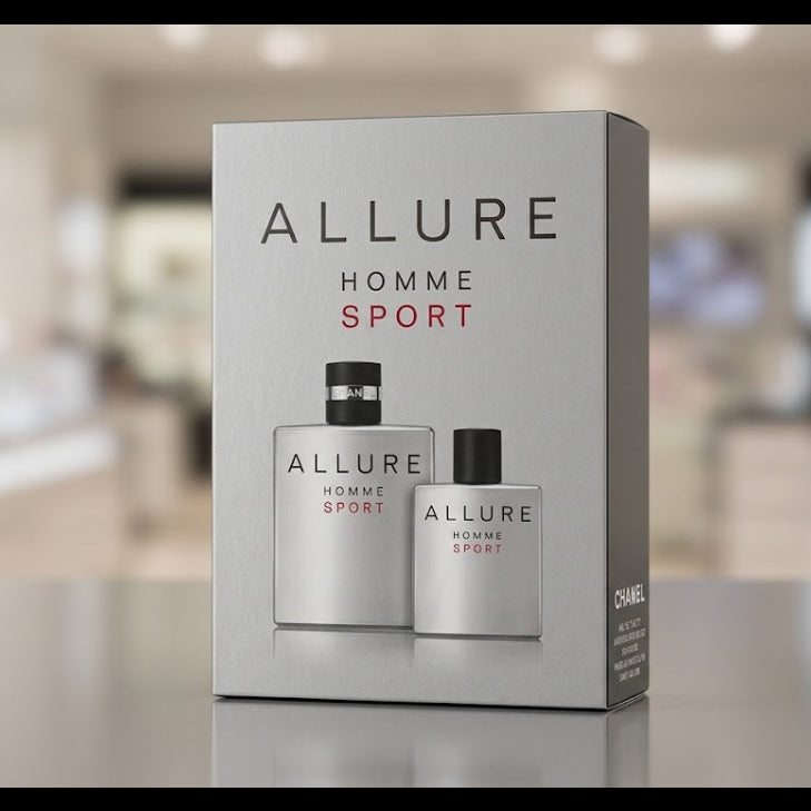 Allure Homme Sport cologne set in a silver-gray box, featuring two matching spray bottles with black caps, displayed on a reflective surface with a blurred store background.