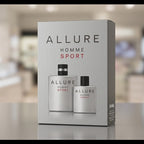 Allure Homme Sport cologne set in a silver-gray box, featuring two matching spray bottles with black caps, displayed on a reflective surface with a blurred store background.